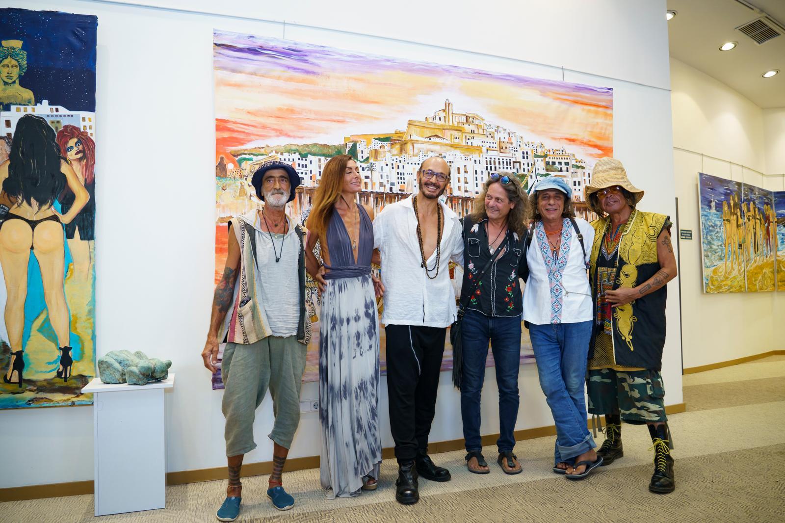 Six guests posed in front of the sunset Dalt Vila canvas at an opening