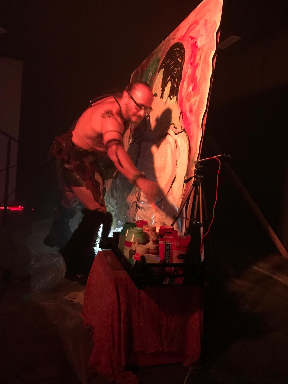 Working into a canvas under red stage light at a night performance