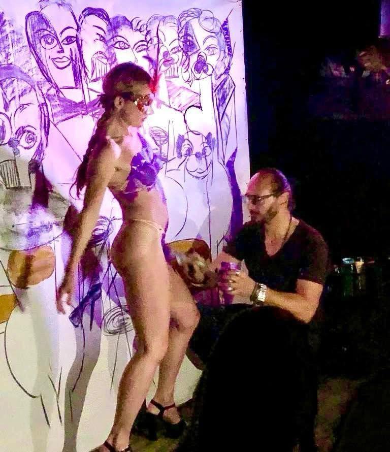 A dancer before a wall of ink figures drawn live at a night performance