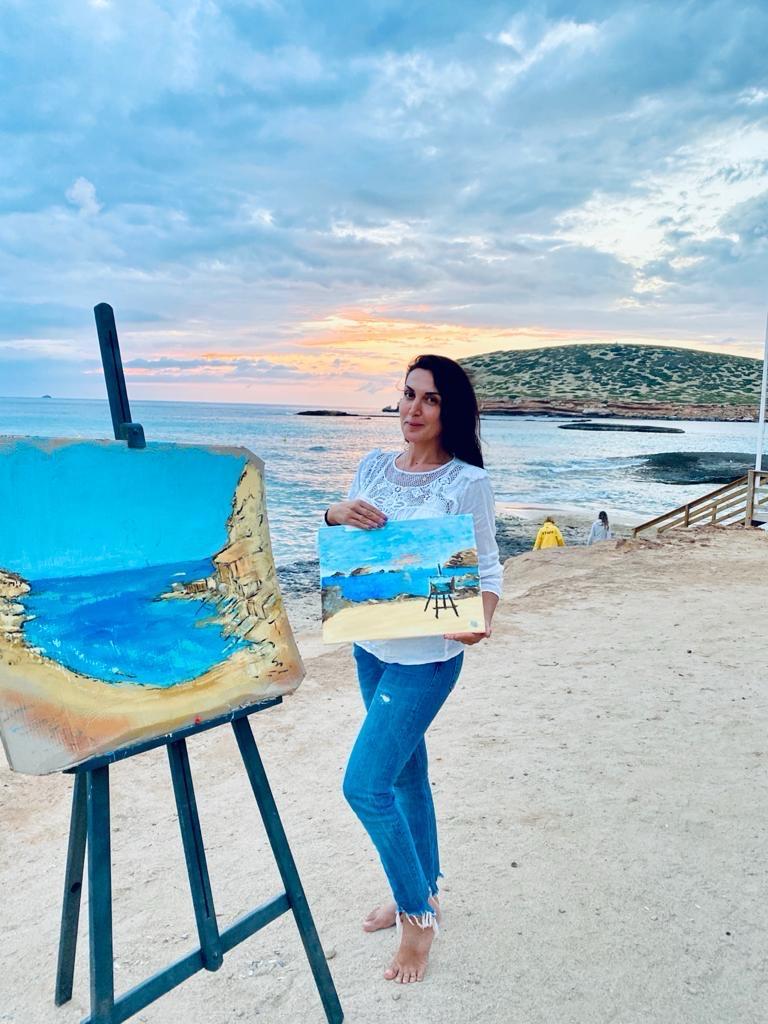 A painter on the shore at sunset, a coastal canvas on the easel beside her